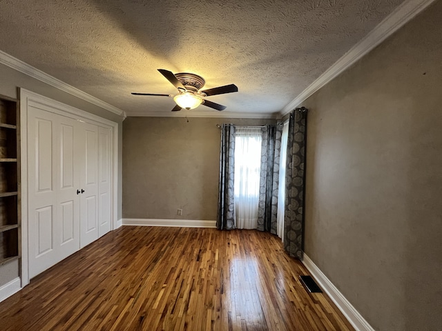 unfurnished bedroom with ornamental molding, ceiling fan, wood-type flooring, and a textured ceiling