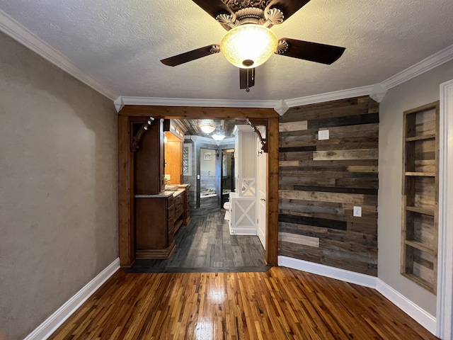 hall featuring crown molding, dark hardwood / wood-style flooring, and wooden walls