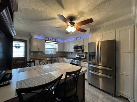 kitchen with appliances with stainless steel finishes, tasteful backsplash, a textured ceiling, sink, and white cabinetry