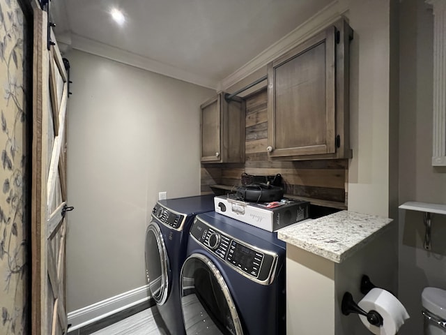 laundry room featuring washing machine and clothes dryer, ornamental molding, cabinets, and light hardwood / wood-style floors