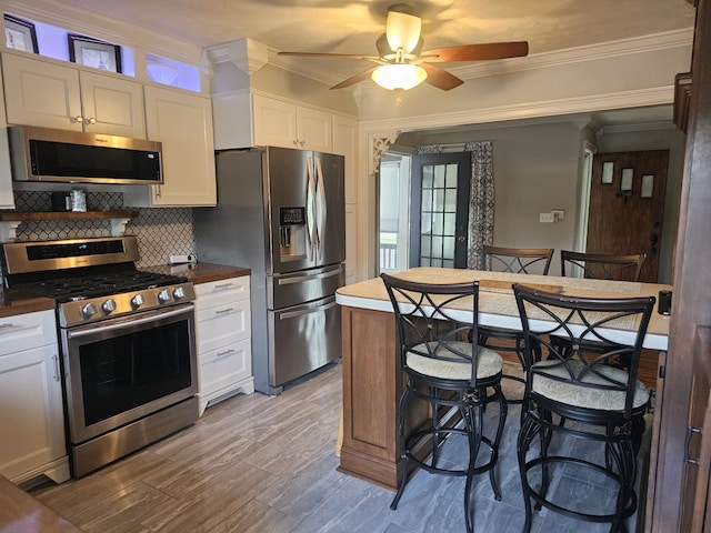 kitchen with white cabinets, appliances with stainless steel finishes, and ornamental molding