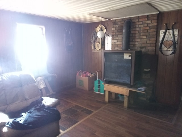 living room with a wood stove, wooden walls, and dark wood-type flooring