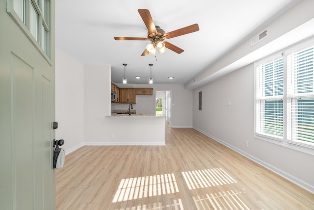 unfurnished living room with ceiling fan, sink, and light wood-type flooring