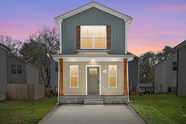 view of front of house with covered porch, a yard, and central air condition unit