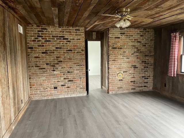 empty room with light hardwood / wood-style flooring, ceiling fan, wooden walls, and wood ceiling