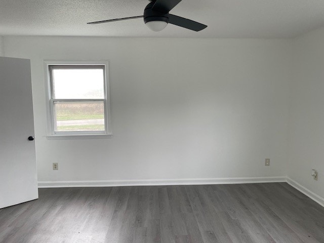 spare room with a textured ceiling, ceiling fan, and dark wood-type flooring