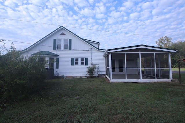 back of property with a sunroom and a lawn