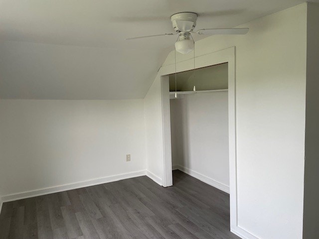 unfurnished bedroom with ceiling fan, dark hardwood / wood-style floors, vaulted ceiling, and a closet