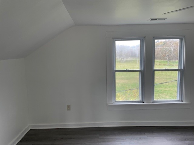 bonus room with dark hardwood / wood-style flooring and vaulted ceiling