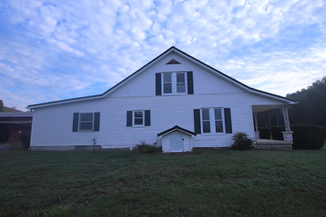 rear view of house featuring a yard and a storage unit