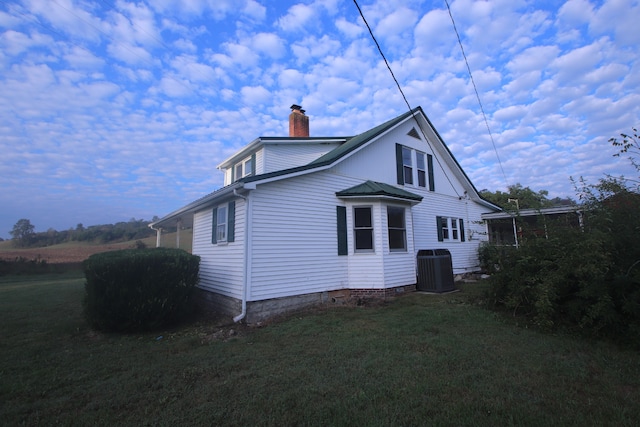 view of home's exterior with a lawn and central AC