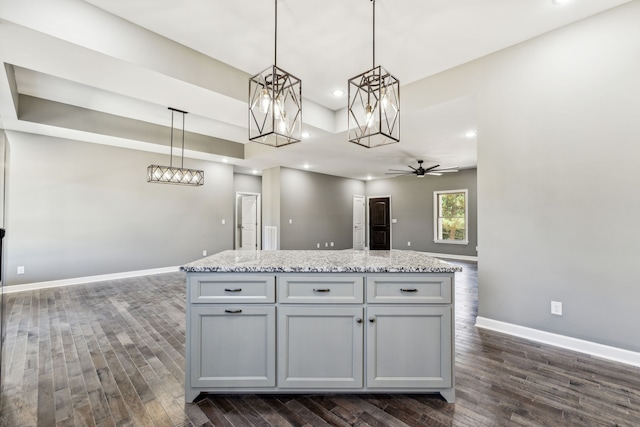 kitchen featuring light stone countertops, a center island, pendant lighting, and dark hardwood / wood-style floors