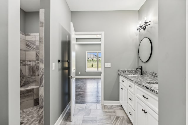 bathroom featuring vanity, tiled shower, and wood-type flooring