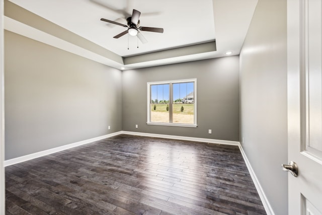 spare room featuring ceiling fan, a tray ceiling, and dark hardwood / wood-style floors