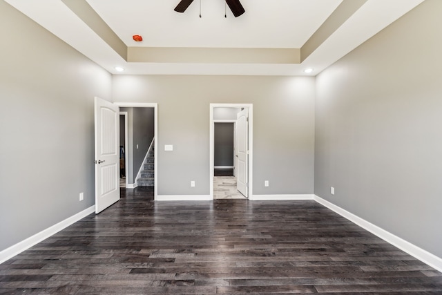 unfurnished bedroom with a spacious closet, ceiling fan, and dark wood-type flooring