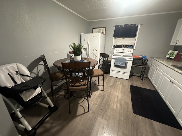 dining area with ornamental molding and light wood-type flooring