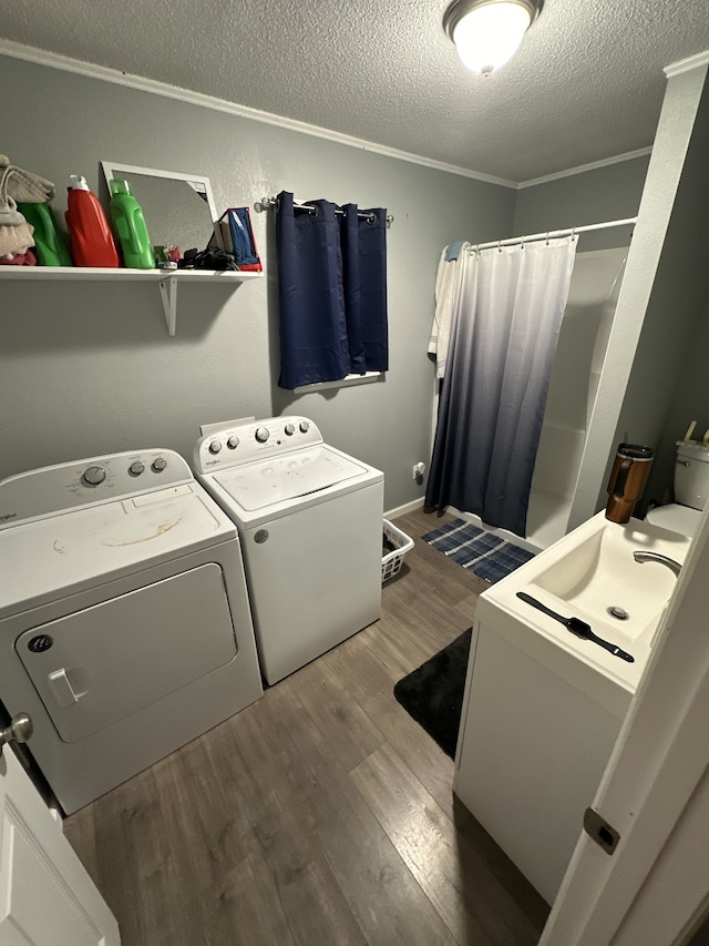 washroom featuring washing machine and dryer, ornamental molding, a textured ceiling, and hardwood / wood-style flooring