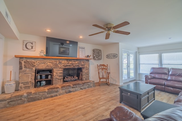 living room featuring a fireplace, french doors, light wood-type flooring, and ceiling fan