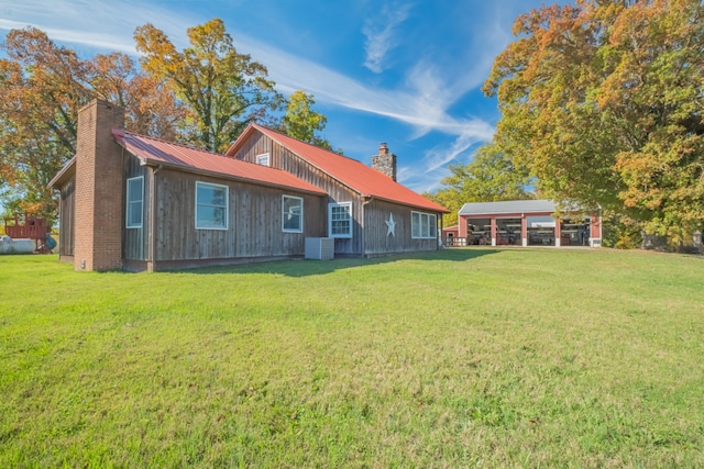 rear view of house with central air condition unit and a yard