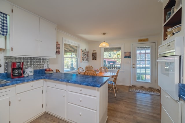 kitchen featuring decorative light fixtures, kitchen peninsula, white cabinetry, and oven