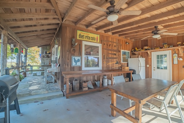 unfurnished dining area featuring vaulted ceiling with beams, ceiling fan, wooden walls, and wood ceiling