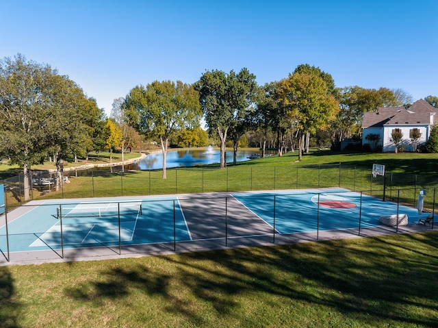 view of tennis court with a water view, community basketball court, fence, and a yard