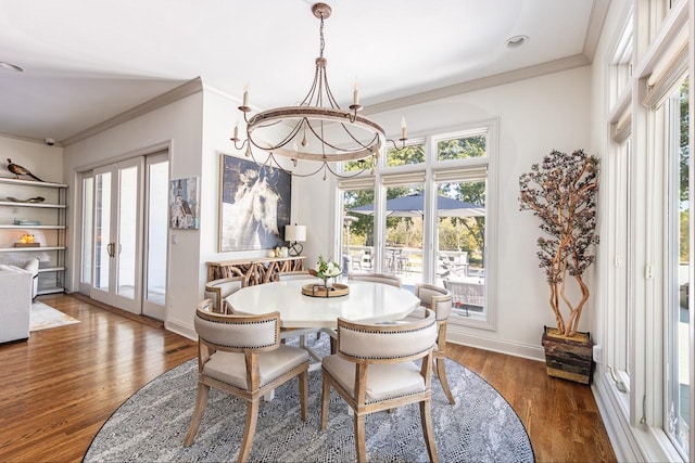 dining room with ornamental molding, healthy amount of natural light, wood finished floors, baseboards, and a chandelier