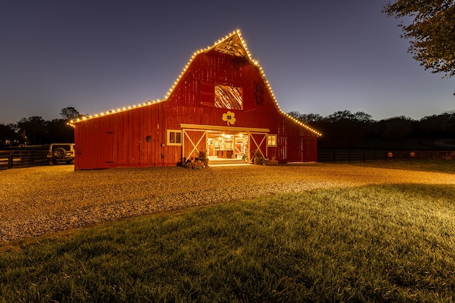 view of barn with fence and a yard