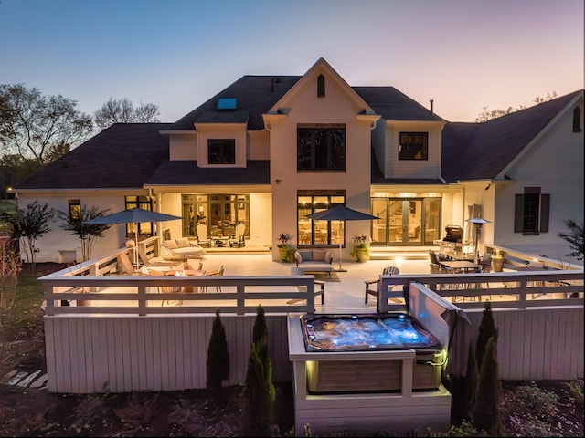 back of property at dusk featuring a covered hot tub and a wooden deck