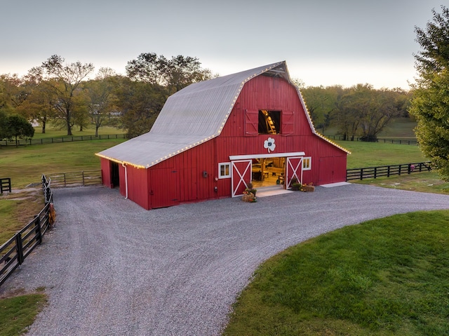 view of barn featuring a rural view, a yard, and fence