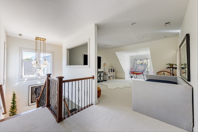 hallway with visible vents, carpet floors, an upstairs landing, and an inviting chandelier