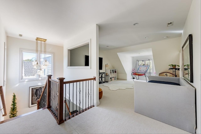 hall featuring an upstairs landing, carpet flooring, and plenty of natural light