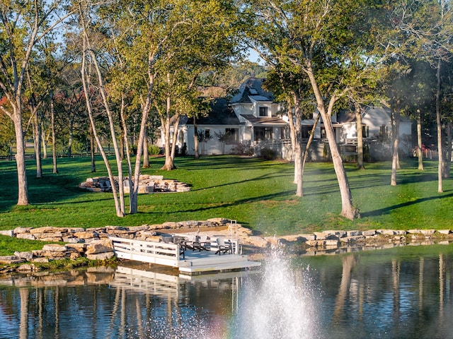 view of home's community featuring a dock, a water view, and a lawn