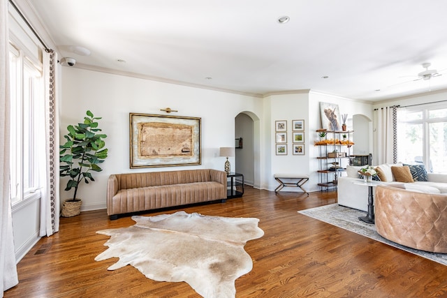 living area featuring baseboards, arched walkways, and wood finished floors