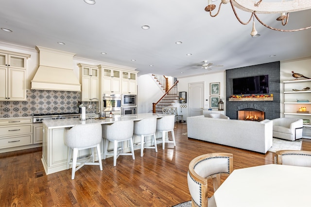 kitchen featuring premium range hood, a fireplace, stainless steel appliances, and cream cabinetry