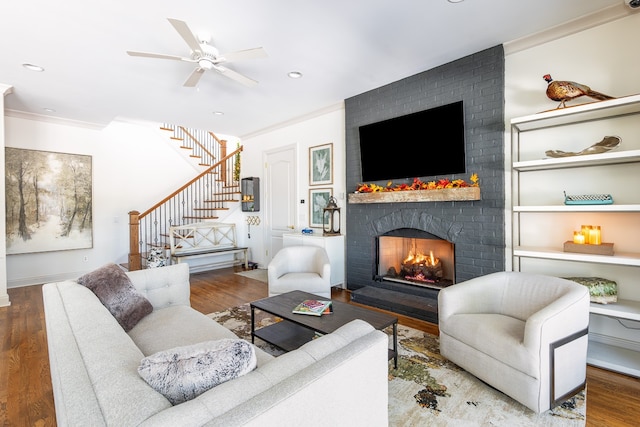 living area with recessed lighting, stairway, ornamental molding, a brick fireplace, and wood finished floors