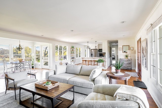 living room featuring wood finished floors, ornamental molding, a chandelier, recessed lighting, and baseboards