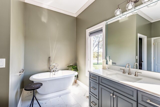 full bath with marble look tile flooring, baseboards, a freestanding tub, vanity, and crown molding