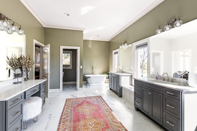 full bathroom featuring a freestanding tub, a sink, marble finish floor, ornamental molding, and plenty of natural light