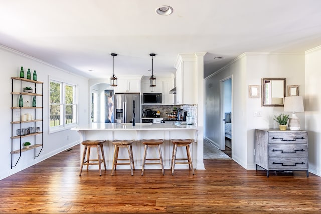 kitchen featuring black microwave, arched walkways, white cabinetry, stainless steel refrigerator with ice dispenser, and tasteful backsplash