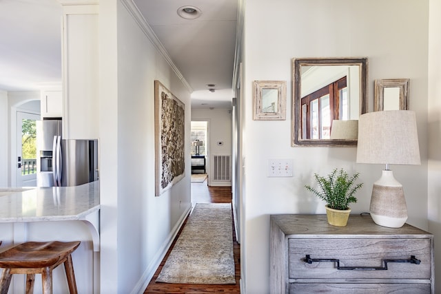 corridor featuring visible vents, ornamental molding, a wealth of natural light, and wood finished floors