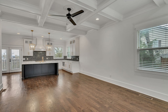 kitchen featuring decorative backsplash, dark wood-type flooring, decorative light fixtures, white cabinets, and a center island