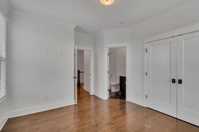 unfurnished bedroom featuring ensuite bath, wood-type flooring, and ornamental molding