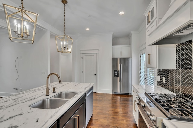 kitchen with appliances with stainless steel finishes, premium range hood, light stone counters, sink, and hanging light fixtures