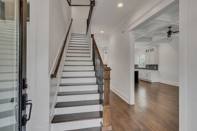 staircase featuring coffered ceiling, ceiling fan, crown molding, beamed ceiling, and hardwood / wood-style floors