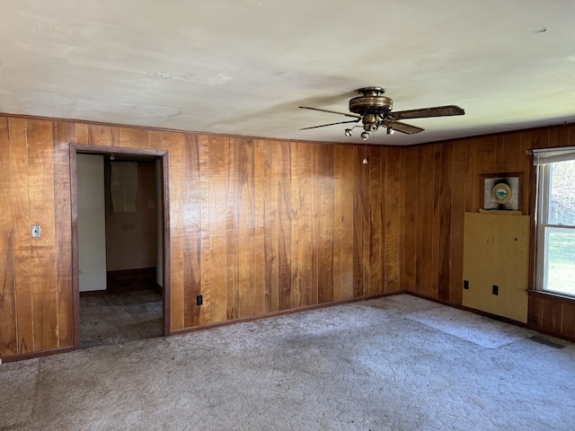 empty room with carpet, ceiling fan, and wooden walls