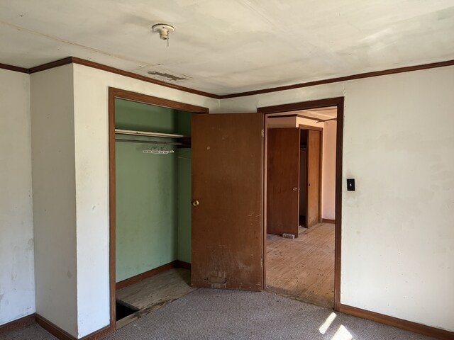 unfurnished bedroom with crown molding, a closet, and wood-type flooring