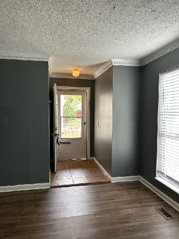 doorway to outside featuring a textured ceiling, hardwood / wood-style flooring, and ornamental molding