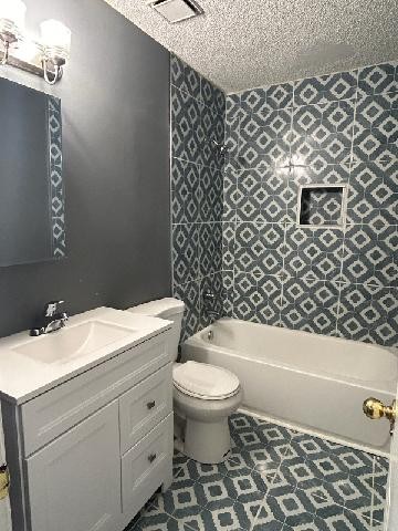 full bathroom featuring vanity, a textured ceiling, bathing tub / shower combination, and toilet