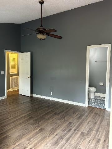 unfurnished bedroom with a textured ceiling, dark hardwood / wood-style floors, ceiling fan, and ensuite bathroom